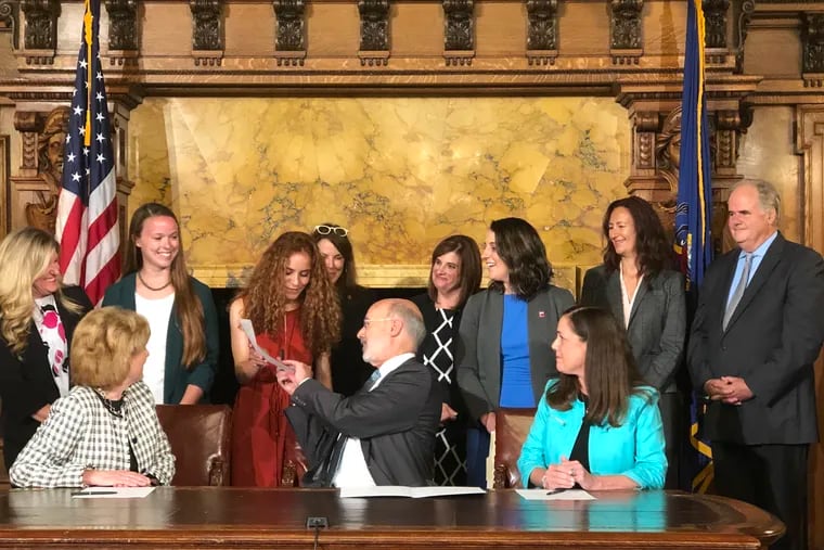 Gov. Tom Wolf hands a signed copy of legislation to strengthen campus sexual assault reporting procedures to Adrianna Branin, a senior at Indiana University of Pennsylvania and a sexual assault reform advocate.