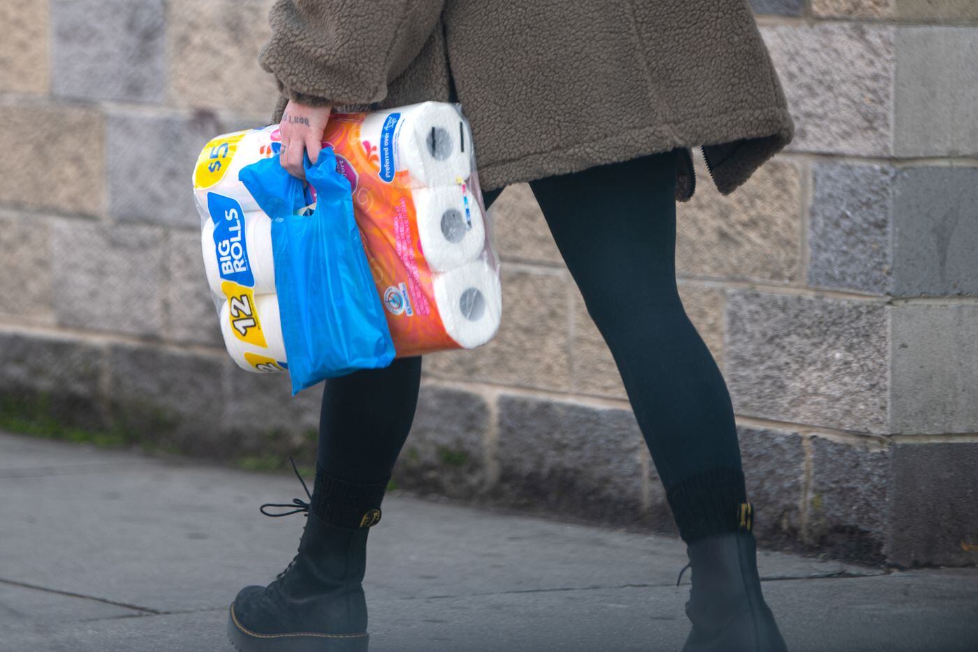 An unidentified woman walks carrying toilet paper rolls in Philadelphia, Pa. Tuesday, March 17, 2020. The household staple has consistently been out of stock during the coronavirus outbreak.