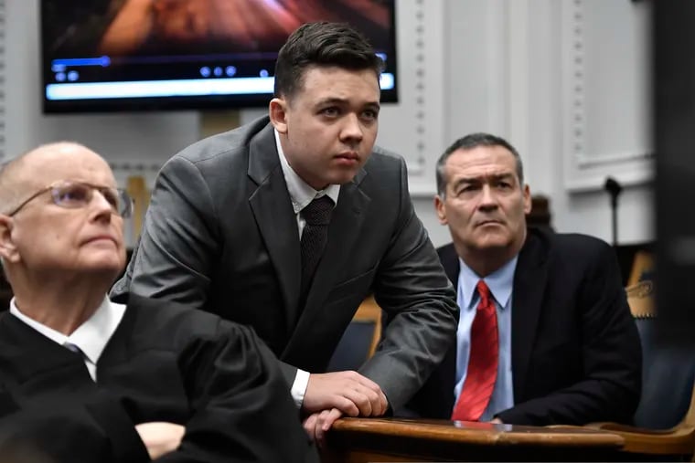 Judge Bruce Schroeder (left), Kyle Rittenhouse (center) and his attorney Mark Richards watch an evidence video in question on a screen during proceedings at the Kenosha County Courthouse in Kenosha, Wis., on Nov. 12, 2021. As Rittenhouse’s trial has played out, moments of apparent deference to the defendant by the judge have struck observers as curiously different from other murder proceedings.