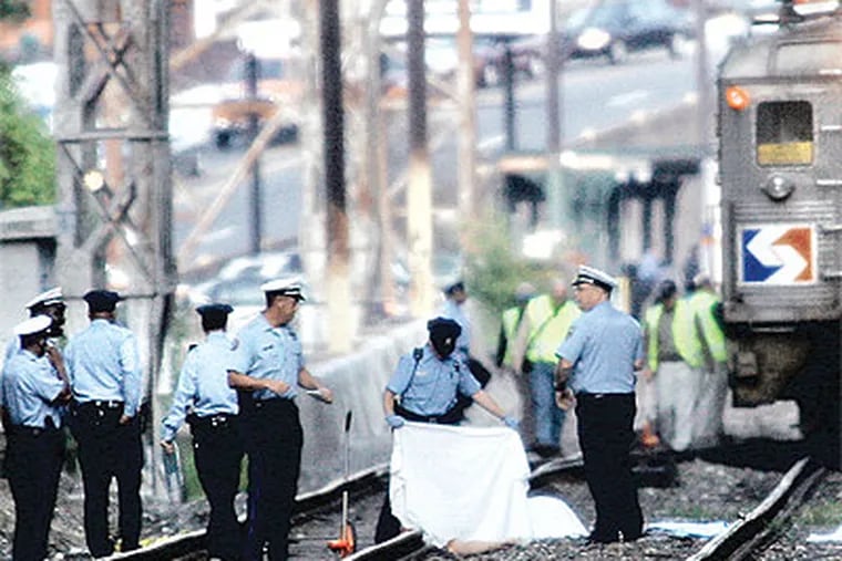 Police cover the body of a suicide by rail on the tracks near School House Lane in East Falls. The 2008 incident occurred during the morning commute and shut down service. In recent years, there have been more than a dozen such suicides in the city. (Alejandro A. Alvarez / Staff Photographer)