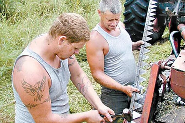Tim Coulter (right) and son Josh work on their tractor. A gas-lease deal last year saved their Wayne County farm from foreclosure. (ANDREW MAYKUTH / Staff)