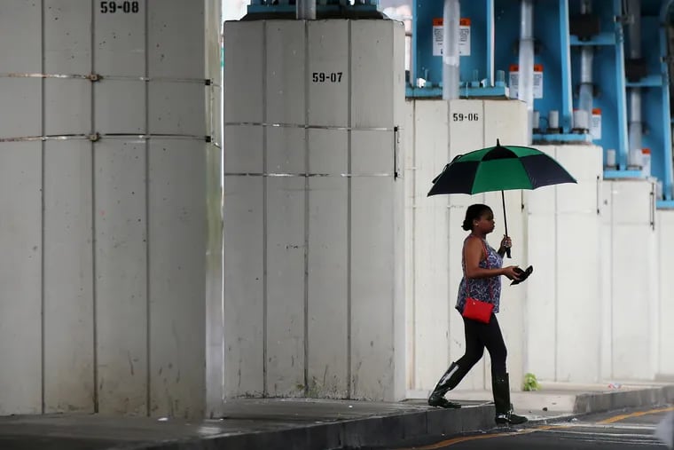 A woman walking under Frankford El tracks in last week's rain at 60th Street. TIM TAI / Staff Photographer