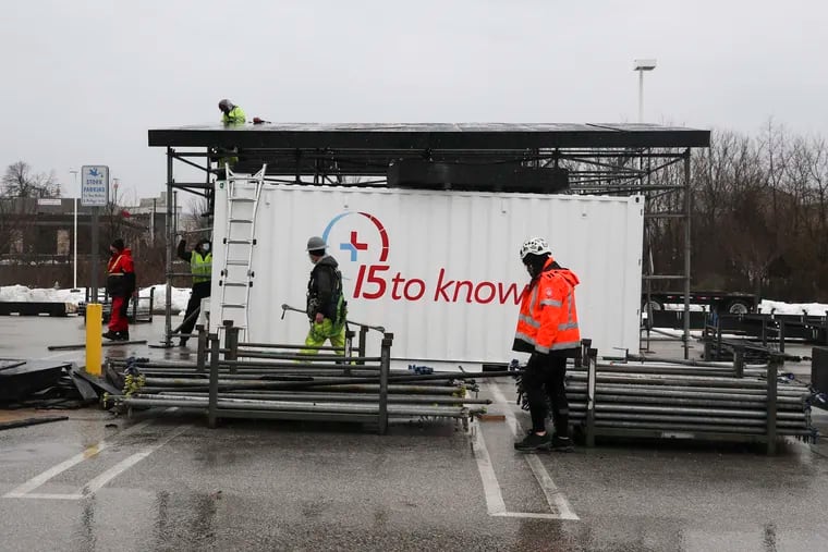 Employees of Mountain Productions construct structures for a COVID-19 vaccination site run by 15toKnow in the parking lot of the former Babies R Us in King of Prussia on Feb. 28.