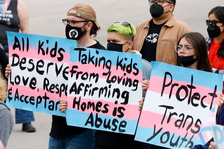 Marlon Peseke, left, Amber Witte, center, and Kenzie Ferguson, 13, right, carry signs during the "Trans Kids Cry For Help" rally outside the Texas Governor's Mansion in Austin, Texas, Sunday, March 13, 2022.