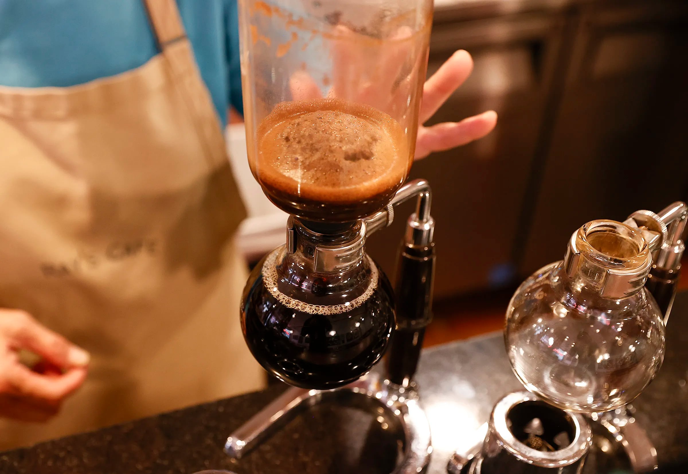 Ray’s Cafe & Tea House owner Grace Chen makes a cup of siphon coffee in the Chinatown coffeehouse.