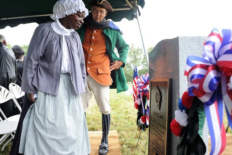 Euell Aira Nielsen (left) of Lansdowne, Pa., portraying Hannah Till, stands with Hendrick Fisher of New Brunswick, N.J. (right) as they view the tombstone honoring Hannah Till on Saturday Oct. 3, 2015 at Eden Cemetery in Collingdale, Pennsylvania.  (William Thomas Cain/For The Inquirer)