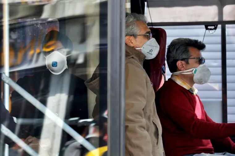 A public bus driver, right, and commuters wear masks to help guard against the Coronavirus in downtown Tehran, Iran, Sunday, Feb. 23, 2020. On Sunday Iran's health ministry raised the death toll from the new virus to 8 people in the country, amid concerns that clusters there, as well as in Italy and South Korea, could signal a serious new stage in its global spread. (AP Photo/Ebrahim Noroozi)