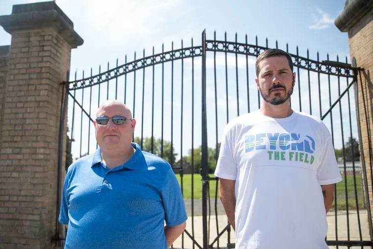 Frankford football coach Bill Sytsma (left) and former Imhotep coach Nick Lincoln outside of the locked gates of Frankford Stadium in Philadelphia. The former coaching rivals are now teammates in Beyond the Field, a violence prevention program designed to provide leadership training and football-related workouts for high school athletes whose seasons have been scuttled by COVID-19. The coaches joined forces in part because both have recently had players killed by gun violence.