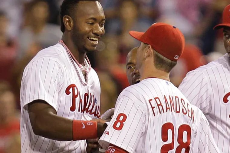 Domonic Brown (left) is congratulated by Kevin Frandsen (28) and John Mayberry Jr, right, after making the game-winning hit to defeat the Colorado Rockies 5-4 in a baseball game, Thursday, Aug. 22, 2013, in Philadelphia. (Laurence Kesterson/AP)