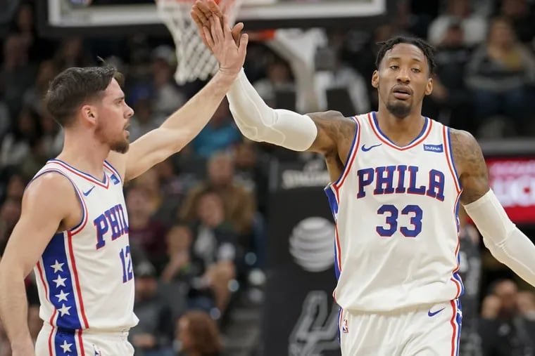 Sixers’ guardT.J. McConnell, left, and forward Robert Covington celebrate a basket during the first half of the team’s win over the Spurs on Friday.