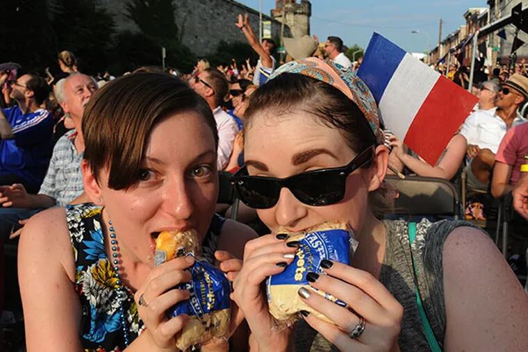 Gabriela Marcu and Michele Frederick eat Tastykake butterscotch krimpets that were tossed off the top of Eastern State Penitentiary during the 20th anniversary event commemorating Bastille Day at Eastern State Penitentiary July 13, 2014.  ( CLEM MURRAY / Staff Photographer )