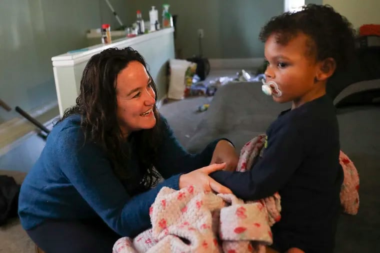 Kori Yancey (left) tries to get the attention of Carter Daily, 2, whom she cares for in the Lansdale apartment he shares with his mother, Erica Carter, who works an overnight shift. Yancey is an employee of Along the Way, a nonprofit that provides overnight daycare for low-income, single mothers who work night shifts.