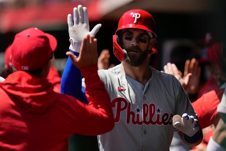 The Phillies' Bryce Harper celebrates in the dugout after hitting a two-run homer in the third inning on Thursday in Cincinnati.