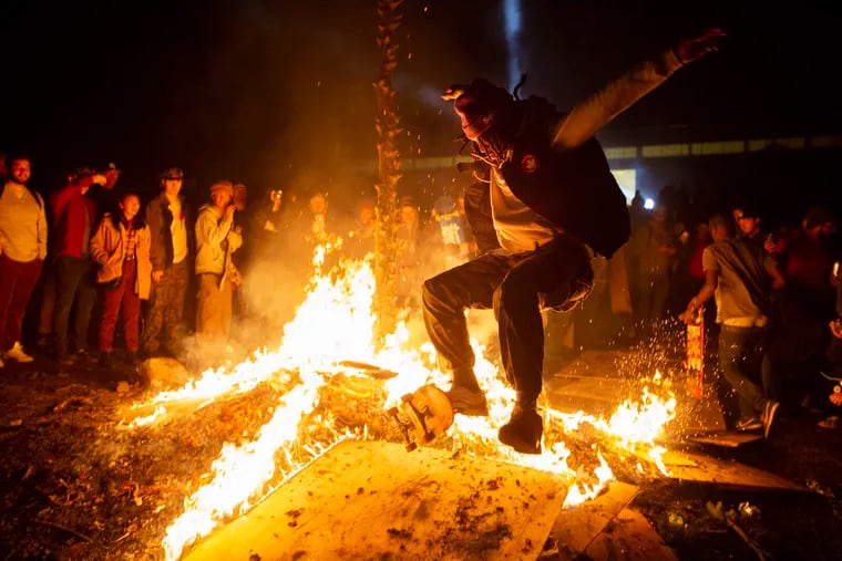 Patrice Southerland skates over a fire, which was built with the wood from skate ramps during Bam Margera's West Chester party at Castle Bam Thursday, December 13, 2018.