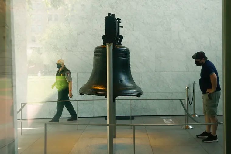 A masked visitor looks at the Liberty Bell as a masked National Park Ranger walks past at the Independence National Historical Park in September.