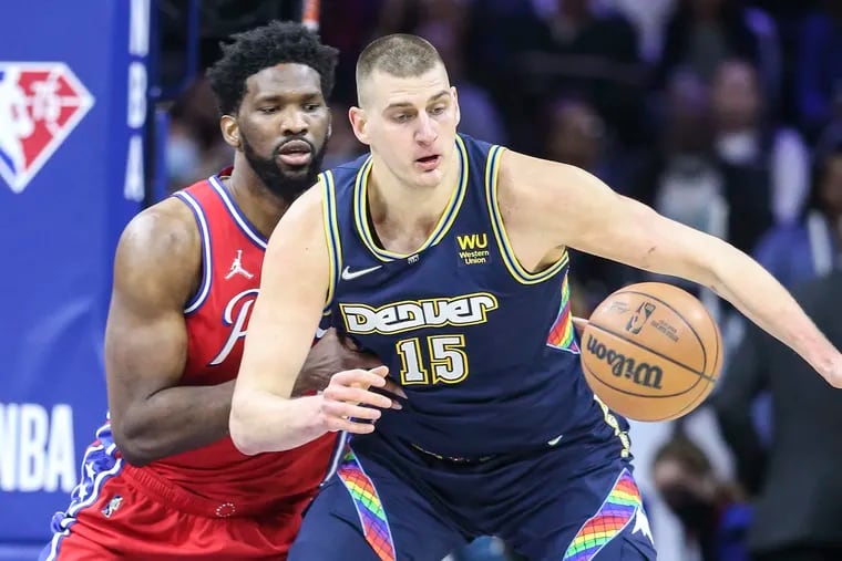 The Denver Nuggets' Nikola Jokić tries to corral a loose ball ahead of the Sixers' Joel Embiid at the Wells Fargo Center on March 14, 2022, in Philadelphia.