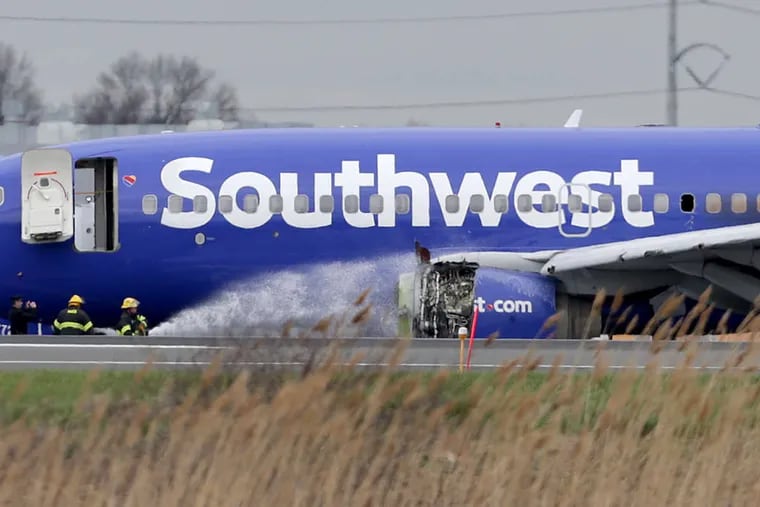 Firefighters spray a Southwest Airlines plane with a damaged engine at Philadelphia International Airport on Tuesday.