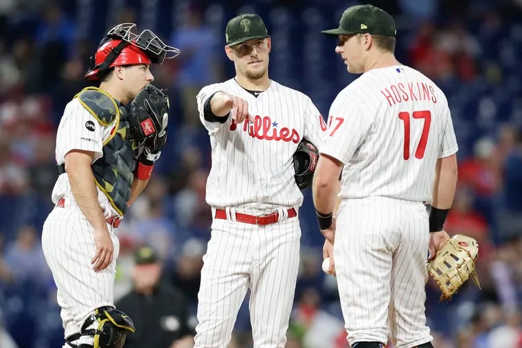Cole Irvin conferences with J.T. Realmuto (left) and Rhys Hoskins during the Phillies' series against the Rockies.