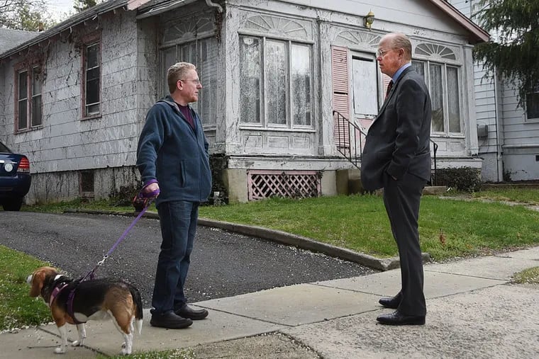 Harvard Avenue resident Ric Schoeffling, left, talks with Collingswood, N.J. Mayor Jim Maley  as he walks his dog Belle in front of one of the long-vacant houses in town.