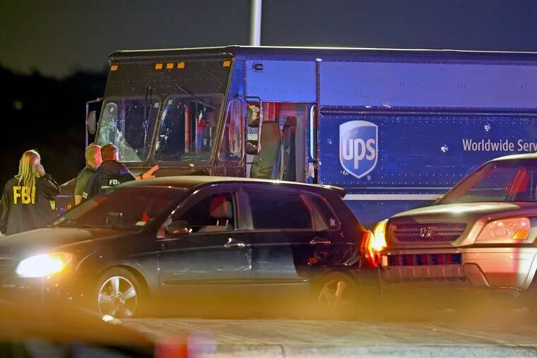 Law enforcement stand near a vehicle that appears to be part of the crime scene where four people were killed, Thursday, Dec. 5, 2019 in Miramar, Fla. The FBI says four people, including a UPS driver, were killed after robbers stole the driver's truck and led police on a chase that ended in gunfire at a busy Florida intersection during rush hour.