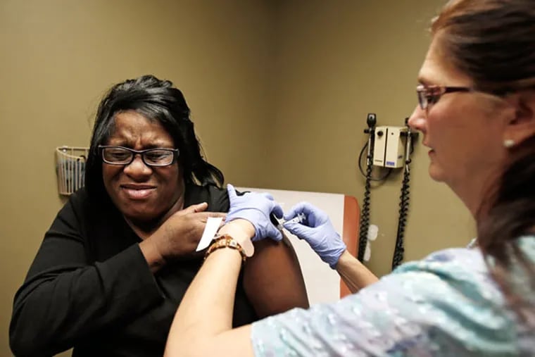 In this 2013 photo, nurse Debbie Smerk (right) administers a flu shot to Pamela Black at MetroHealth in Cleveland.