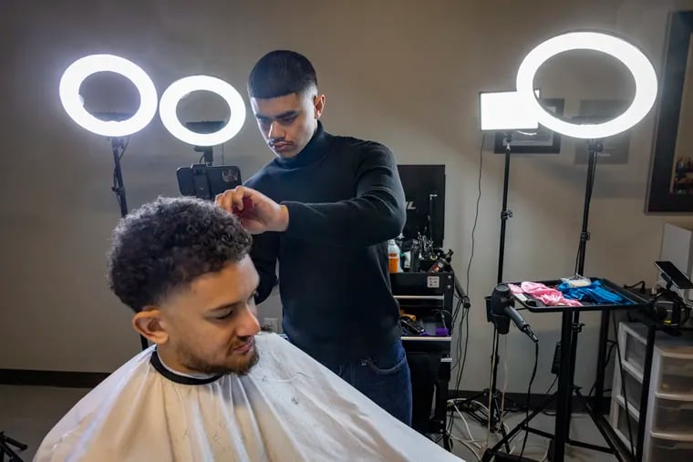 Matheo Olaya, a client of Kenneth’s for about 3 years gets hair cut. Kenneth Carruth, 20, barber at 3400 J. Street in Philadelphia. Picture taken at his shop on Wednesday, January 18, 2023. Kenneth is a youtuber, and social media content producer.
