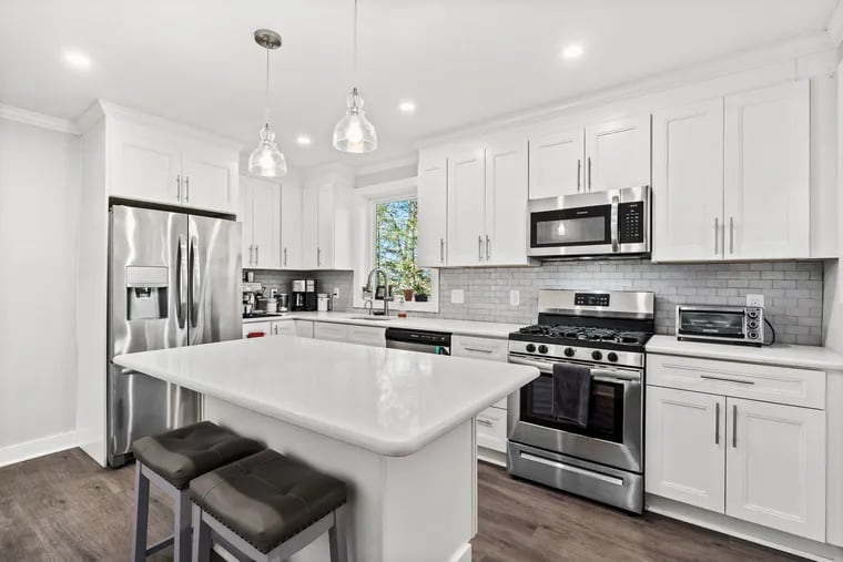 The redone kitchen has white cabinetry, an island with seating, stainless steel appliances, and crown molding.