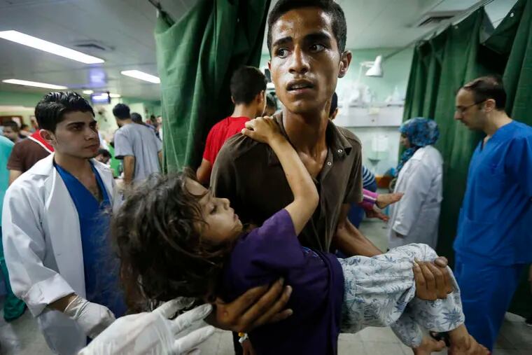 A Palestinian youth carries a child wounded in the attack on the U.N. school in Beit Hanoun. The violence in Gaza was raising protests in the West Bank.