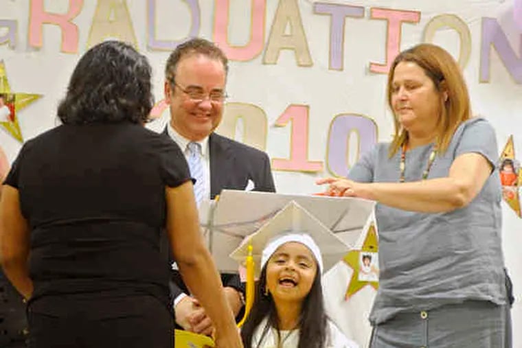 Brenda Lopez is all smiles as she and her mother, Sofia Dominguez, receive &quot;diplomas&quot; from Juan Guerra, head of Accion Communal Latinoamericana de Montgomery County, and teacher Marla Benssy for completing the literacy program. Below, graduates-to-be (from left) Leonardo Zavaleta, Kevin Hernandez, and Gustavo Huelilt adjust their mortarboards before the ceremony.