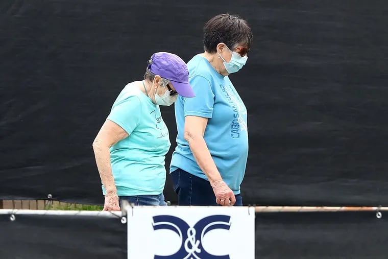 A pair of women wearing masks last week behind a blackened fence where quarantined Grand Princess cruise ship passengers are isolated in a housing area at Dobbins Air Reserve Base in Marietta, Ga.