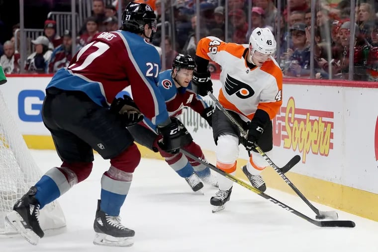 Joel Farabee of the Flyers brings the puck off the boards against Ryan Graves (left) and Nathan MacKinnon of Colorado.