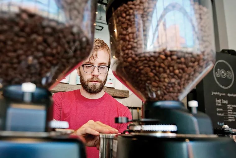 Barista David Thompson grinds coffee beans at Joe Coffee on the 3200 block of Chestnut Street in University City. The small chain received loans from Bond Street to open two outlets in Manhattan. (DAVID MAIALETTI/Staff Photographer)