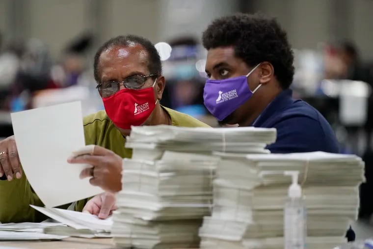 Officials sort ballots during an audit at the Georgia World Congress Center on Saturday, Nov. 14, 2020, in Atlanta. Election officials in Georgia's 159 counties are undertaking a hand tally of the presidential race that stems from an audit required by state law.