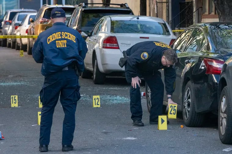 Philadelphia police crime scene unit officers gather evidence. Police investigate a homicide along first block of Redfield Street just below Market in West Philadelphia on Friday morning.