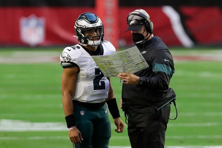 Eagles QB Jalen Hurts and head coach Doug Pederson look over a two-point conversion play against the Cardinals Sunday.