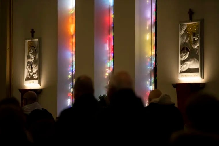 Sunlight streams in through stained glass windows during Mass at St. Cecilia Church in the Fox Chase in 2022.