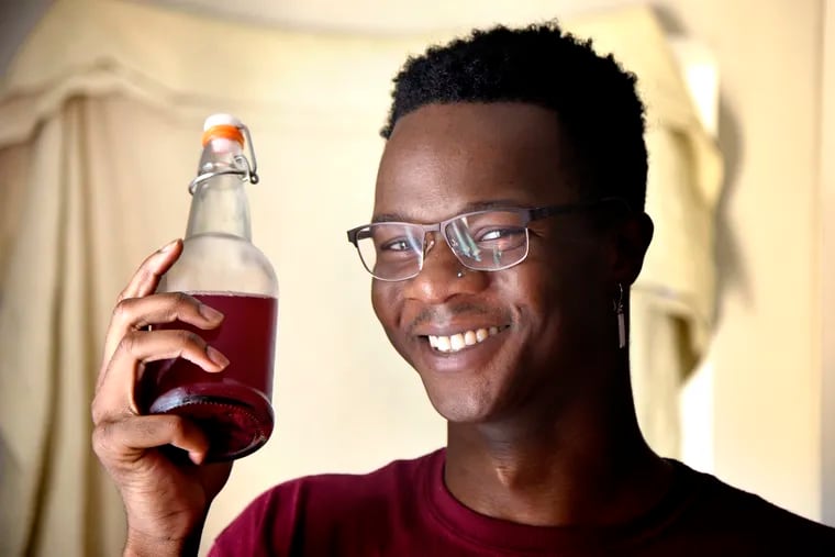 Jamaar Julal, 24, who has a fledgling kombucha business, poses with a bottle of his brew in the kitchen of his Point Breeze home on July 27, 2020.