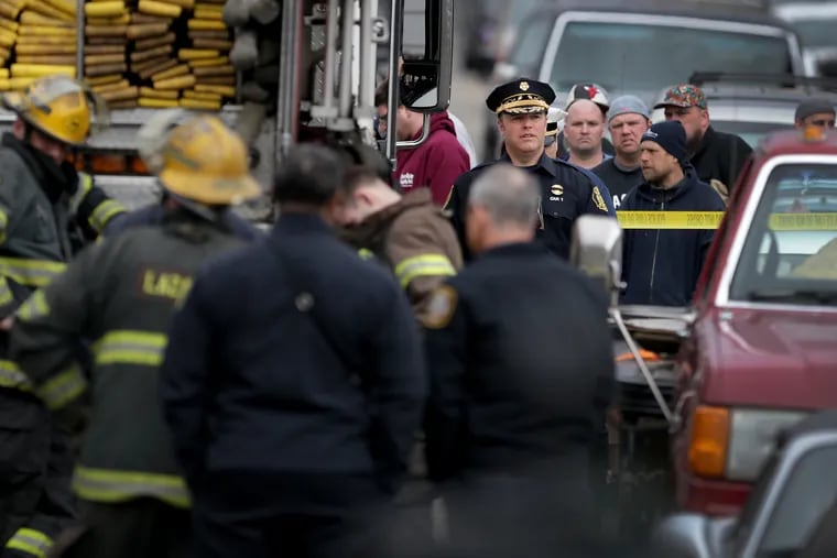 Philadelphia Fire Commissioner Adam Thiel (center background) walks away after talking with family and friends of the victims at the scene of a fatal fire in March.