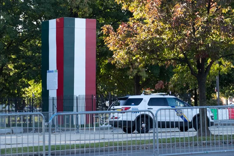 Police keep watch over the the Christopher Columbus statue in Philadelphia on Oct. 7. The statue remains hidden by a plywood box while its fate is decided in the courts, but the box has now been painted with the colors of the Italian flag.