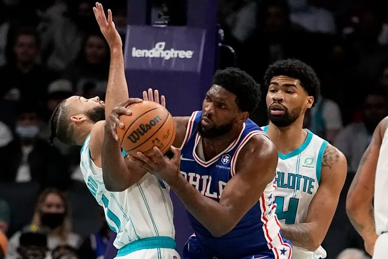 Sixers center Joel Embiid looks to pass between Charlotte Hornets forward Cody Martin (left) and center Nick Richards during the first half Monday.