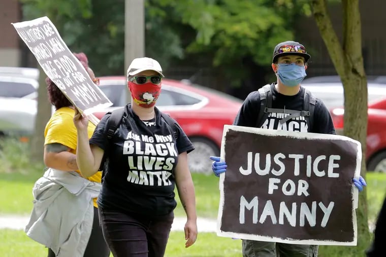A protester holds a sign that reads "Justice for Manny" in this June 5, 2020 photo in Tacoma, Wash.