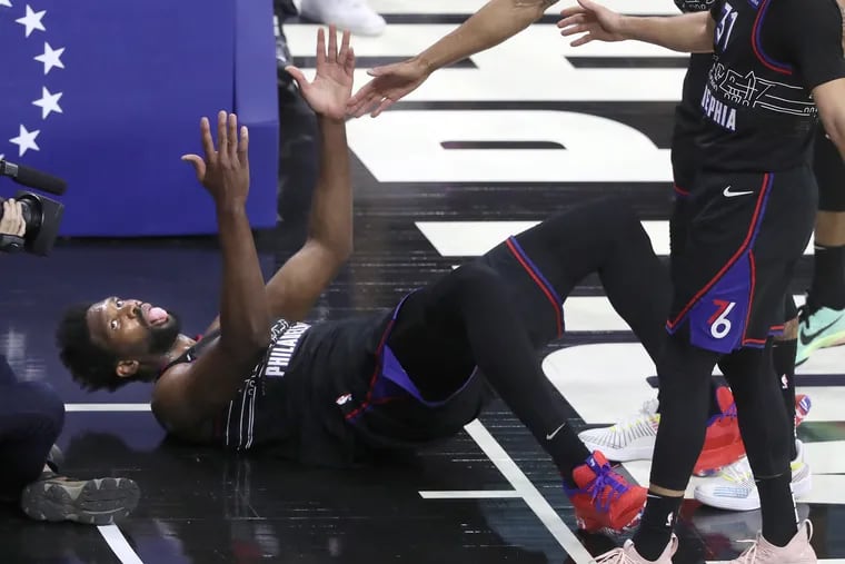 Joel Embiid dances and sticks his tongue out after making a falling shot and being fouled by Robin Lopez of the Wizards during the first half Wednesday at the Wells Fargo Center.