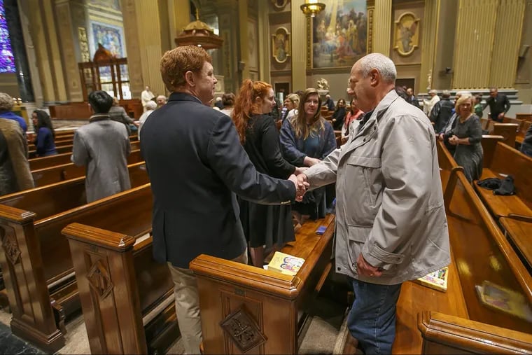 The congregation at the morning mass at St. Peter and Paul on October 28, 2018, shake hands as they offer each other the sign of peace the day after the synagogue shooting in Pittsburgh.