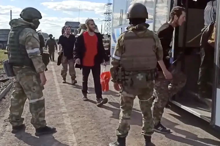 In this photo taken from video released by the Russian Defense Ministry Press Service on Tuesday, Russian servicemen watch Ukrainian servicemen boarding a bus as they are being evacuated from the besieged Azovstal steel plant in Mariupol, Ukraine.