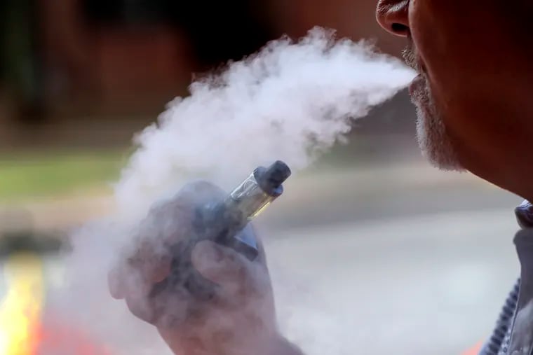 In this Aug. 28, 2019, photo, a man exhales while using an e-cigarette in Portland, Maine. Efforts to ban flavored e-cigarettes and reduce their appeal to youngsters have sputtered under industry pressure in over a half-dozen states this year. The industry and its lobbyists urged lawmakers to leave mint and menthol alone. A proposed ban that President Donald Trump outlined Wednesday, Sept. 11, would supersede any state inaction and includes a ban on mint and menthol. (AP Photo/Robert F. Bukaty)
