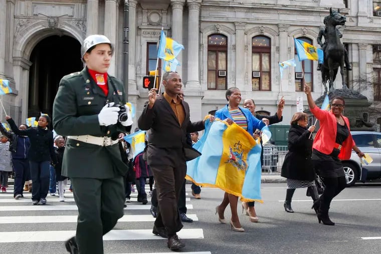 Marvis Frazier (second from left) marches at City Hall with former Inquirer columnist Annette John-Hall (second from right), recipient of the city's 2013 Maneto Award, during Civic Flag Day.
