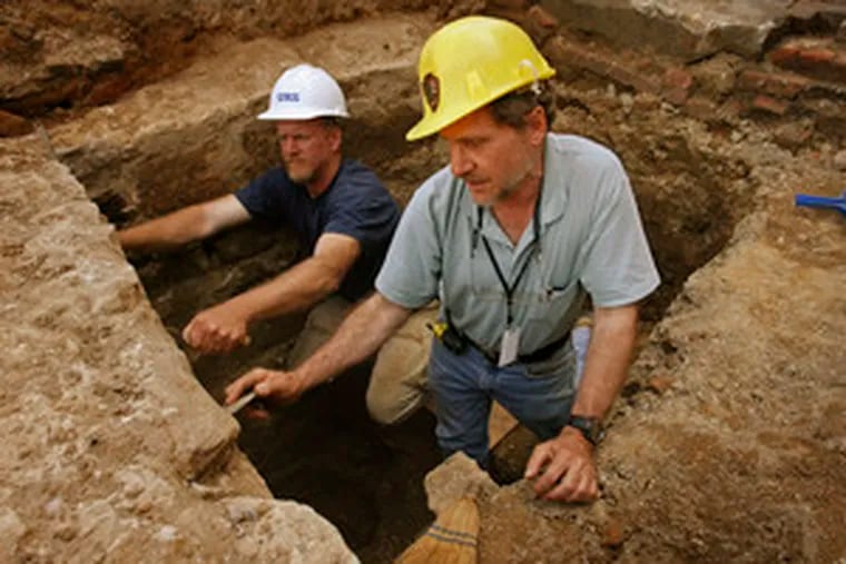 Field director Douglas Mooney (left) and archaeologist Jed Levin clean walls from what they believe may be a cellar.