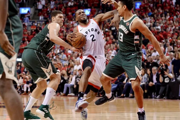 Kawhi Leonard drives to the basket against Milwaukee's Brook Lopez (right) and Malcolm Brogdon during the second overtime of Game 3 on Sunday.