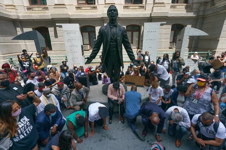 Faith and community leaders and other protesters take a knee in honor of the memory of George Floyd at the Octavius V. Catto Memorial outside of City Hall on June 4.