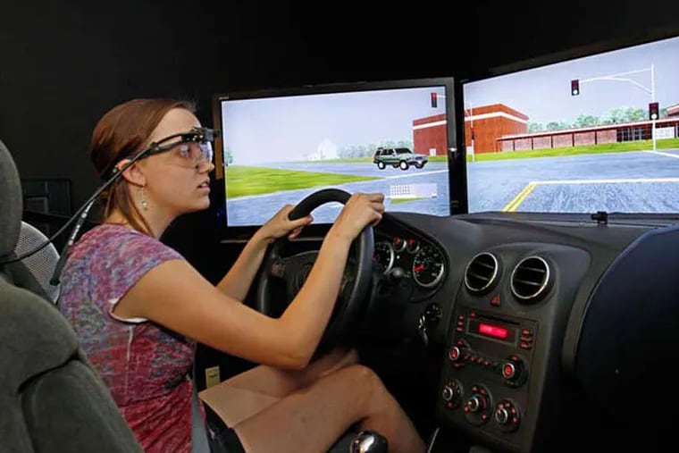 The author, wearing eye-tracking goggles, "drives'' the three-screen simulator as CHOP researchers monitor her to assess her skill.